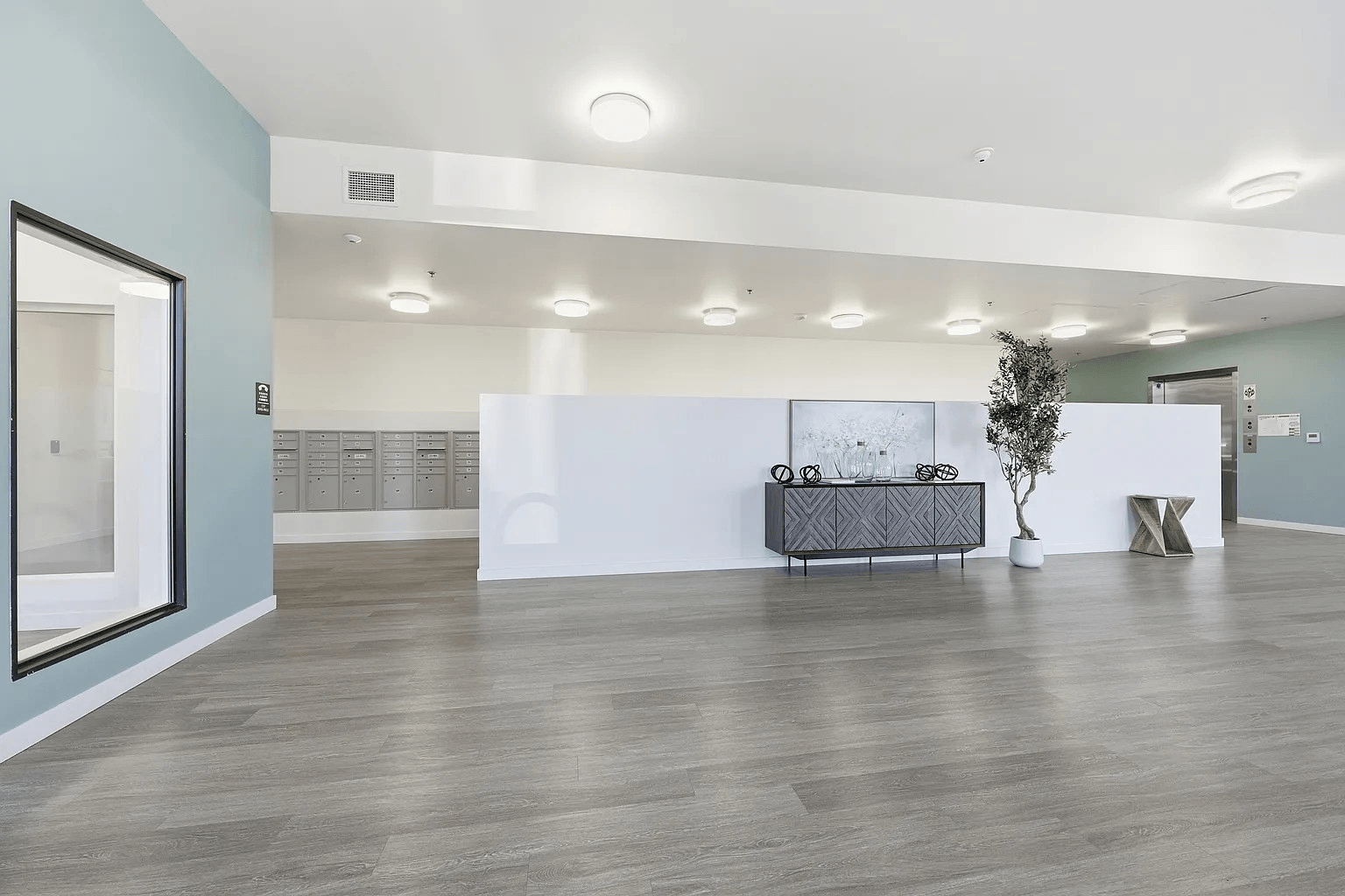 A spacious room with a grey sofa and a white table.